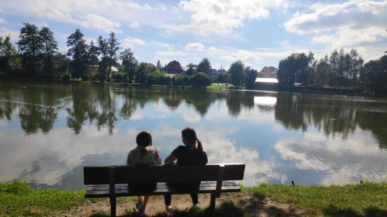 Dziewczyny odpoczywają na ławce nad jeziorem.