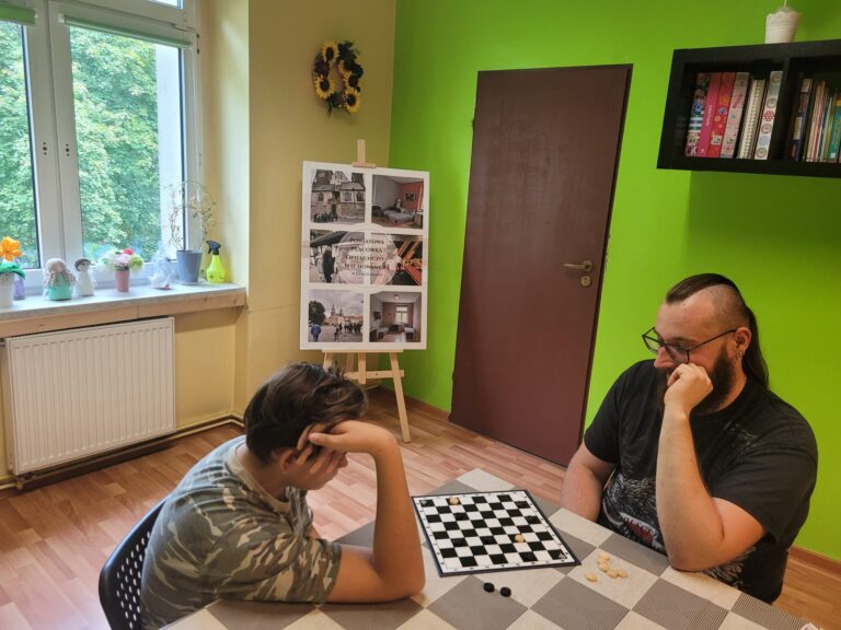 Chłopiec z wychowawcą gra w planszówki.