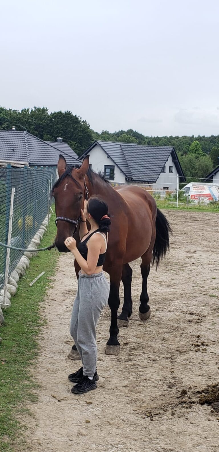 Dziewczyna głaszcze konia podczas zajęć z hipoterapii.