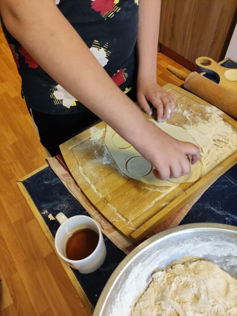 Chłopak przygotowuje ciasto na pierogi w okresie przedświątecznym.